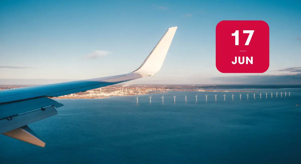 Udsigt fra et flyvindue over en havvindmøllepark med en by i baggrunden og en rød firkant med 17 JUN.