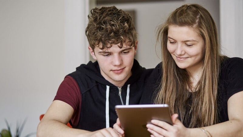 2 unger sidder på tablet og kigger på uddannelsesforum - Danes Worldwide