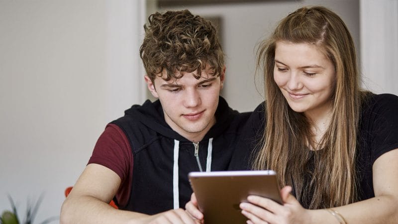 2 unger sidder på tablet og kigger på uddannelsesforum - Danes Worldwide